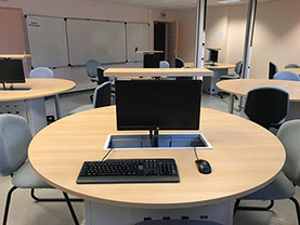 salle multimédia avec table et ordinateur encastrés, une réalisation Riguet Bureautique